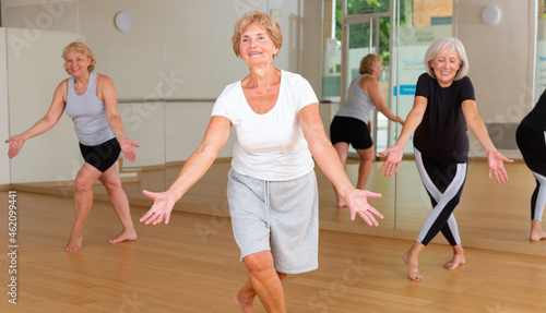 Energetic elderly woman practicing modern vigorous dance movements in group dance class .