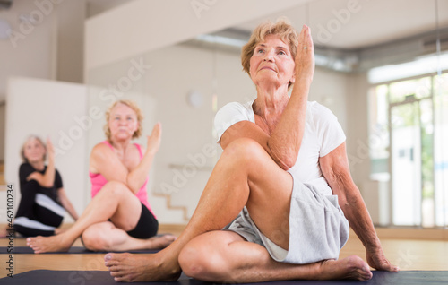 Senior women sitting in lord of the fishes pose during their group yoga training.