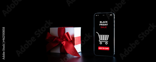 Online shopping gifts. Black Friday banner with internet shopping app on mobile phone, white gifts with red bow falling on black background. Present online concept.