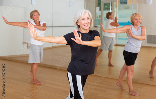Mature women engaged in group training practice active dancing in the studio