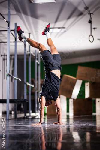 Muscular athlete standing and walking on hands upside down photo