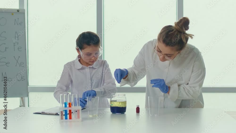 A Teenage Girl With a Teacher in Lab Coats and Safety Glasses Conducts ...
