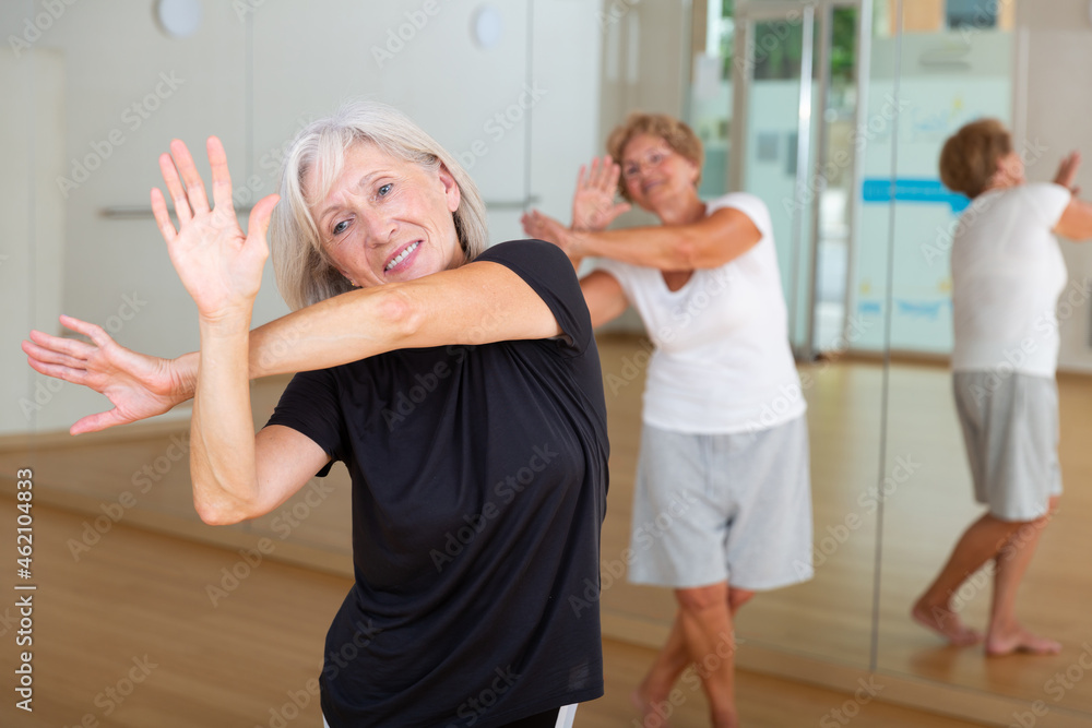 Obraz premium Portrait of an elderly dancing woman practicing vigorous swing at a group training session in the studio of dance