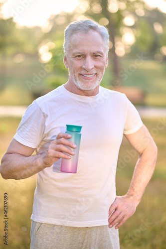 A picture of a man with a bottle of water in hands