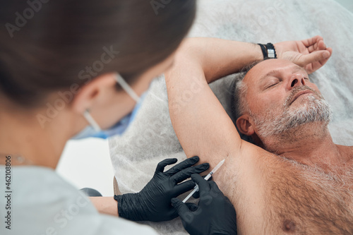 Man receiving underarm treatment in cosmetology clinic