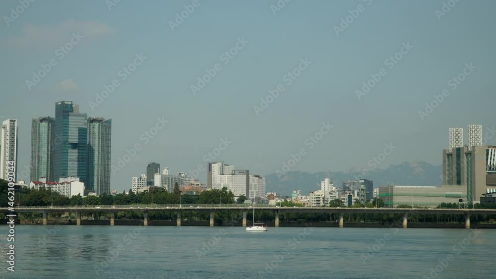 Hangang River with Day Traffic on Gangbyeon Expressway Road and Mapo-gu, Seoul Bukhansan Mountains in Background. Distant view of Unrecognizable Couple Enjoys Private Small Yacht Cruise Voyage Hangang River with Day Traffic on Gangbyeon Expressway Road and Mapo-gu, Seoul Bukhansan Mountains in Background. Distant view of Unrecognizable Couple Enjoys Private Small Yacht Cruise Voyage