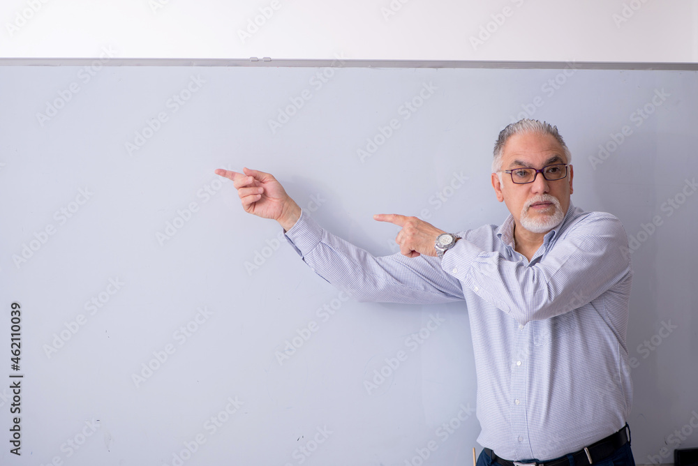Old male teacher in front of whiteboard Old male teacher in front of whiteboard