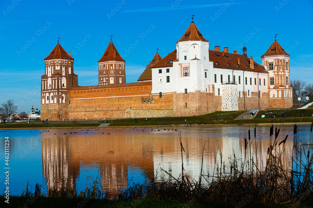 View of architectural ensemble of Mir Castle from pond in sunny winter day, Grodno region, Belarus