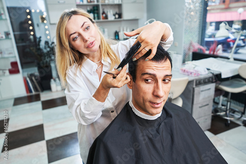 Barber gathering hair with comb and cutting it off