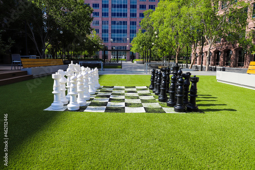 a giant black and white chess set on lush green grass surrounded by lush green and autumn colored trees near buildings at Lenox Park in Brookhaven Georgia USA photo