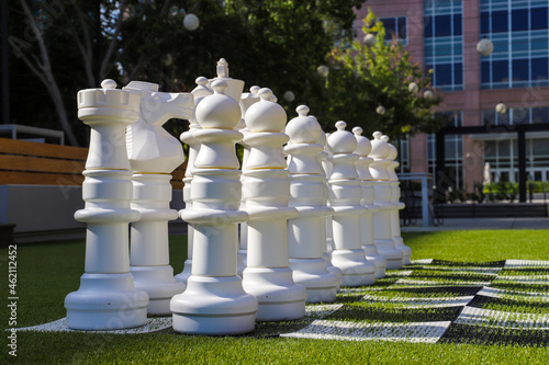 Giant white chess pieces on lush green grass surrounded by lush green trees and red brick buildings at Lenox Park in Atlanta Georgia USA photo