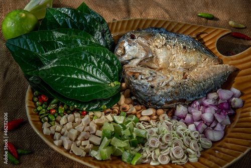 Close-up of Thai Traditional Food : Fried mackerel served with fresh vegetable and herb, This food is thai food call Meuang Mackerel (Maing-Pla-too) menu. Selective focus. photo