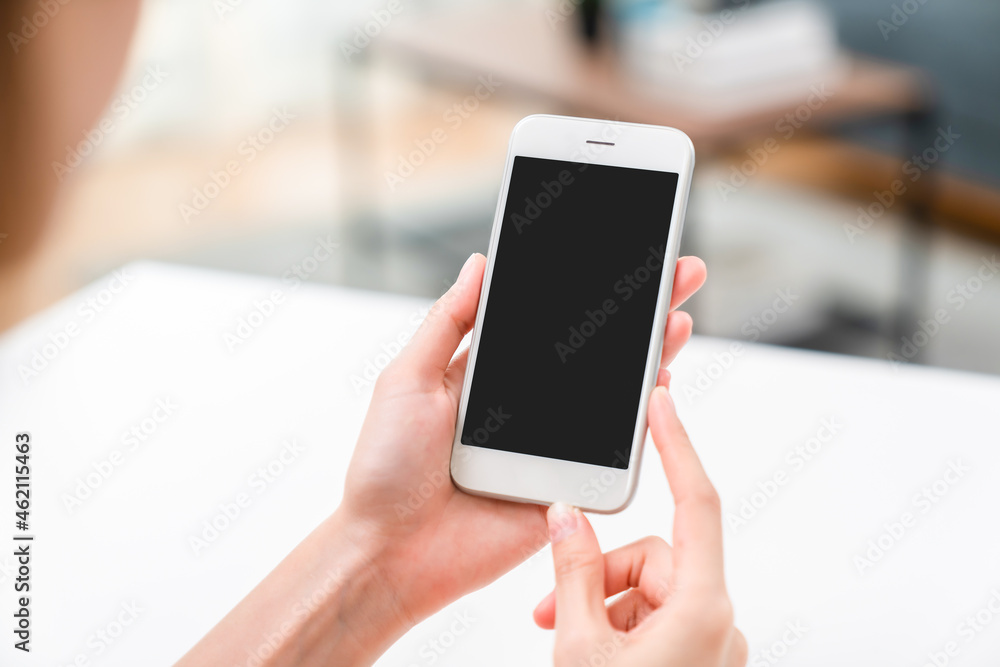 Hand holding smartphone mockup of blank screen on the table. Take your screen to put on advertising.