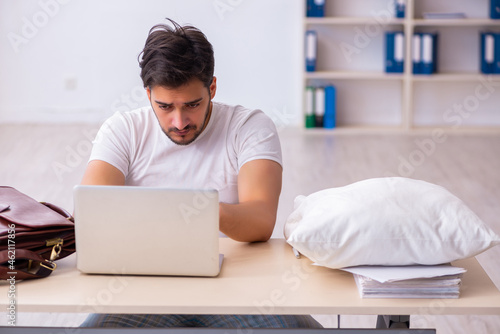 Young male employee coming to work straight from bed