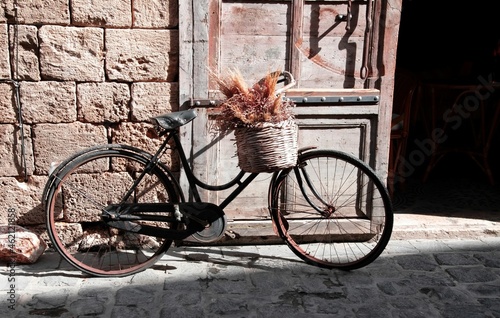vintage bicycle leaning on the old door of a Mediterranean stone house