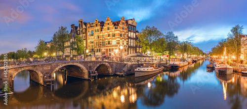Fototapeta Naklejka Na Ścianę i Meble -  Amsterdam, Netherlands. Panorama of the historic city center of Amsterdam. Traditional houses and bridges of Amsterdam small town. A romantic evening and a bright reflection of houses in the water. 