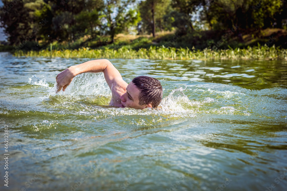 Fototapeta premium The young man swimming in the river