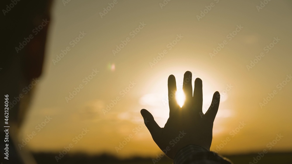 human hand at sunset in the sky, dream of happiness, meditate in the rays of sunlight, catch bright orange light, travel on vacation, harmony of enjoying nature and relaxation, meeting the sunrise