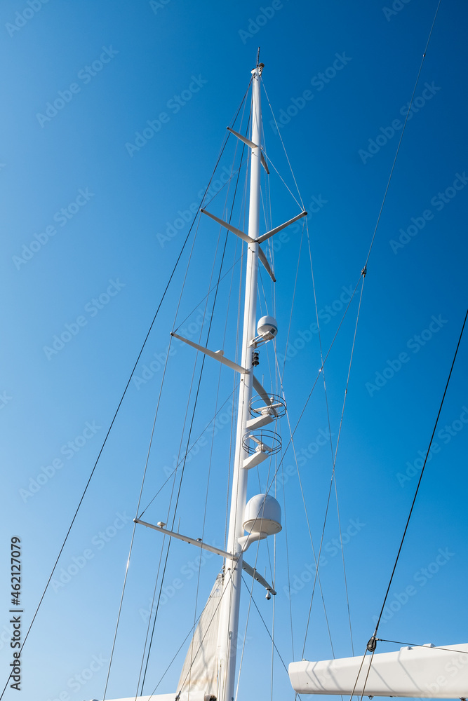 White massive masts on a sailing ship on a solid blue sky background White massive masts on a sailing ship on a solid blue sky background