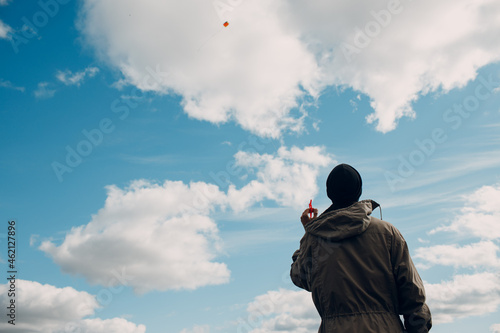 Young man flying a kite against blue sky.