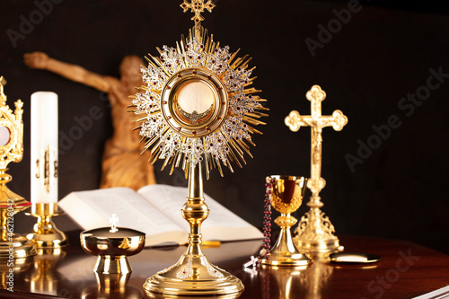 Catholic symbols composition. Religion concept. Jesus figure,The Cross, monstrance,  Holy Bible and golden chalice on the gray background. 