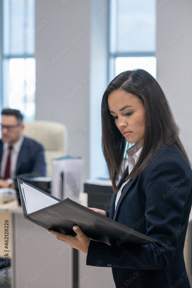 Young brunette businesswoman looking through business contract against male colleague Young brunette businesswoman looking through business contract against male colleague