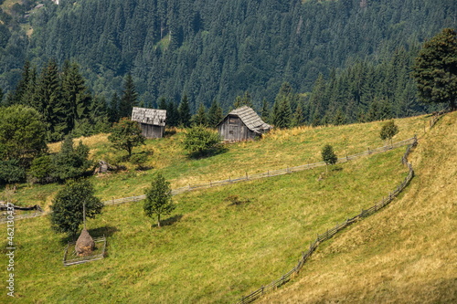 Abandoned buildings in the mountains, wooden houses against the background of rocks, the natural landscape, green meadows and forests