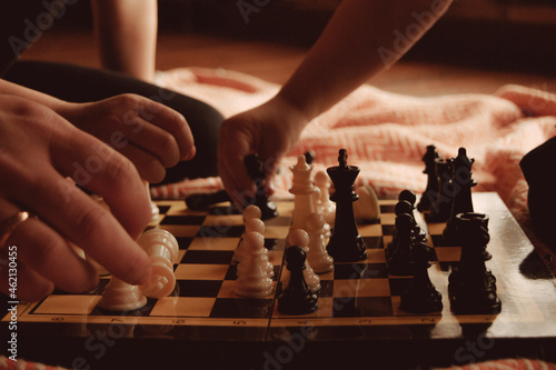 Children playing wooden chess with their parents