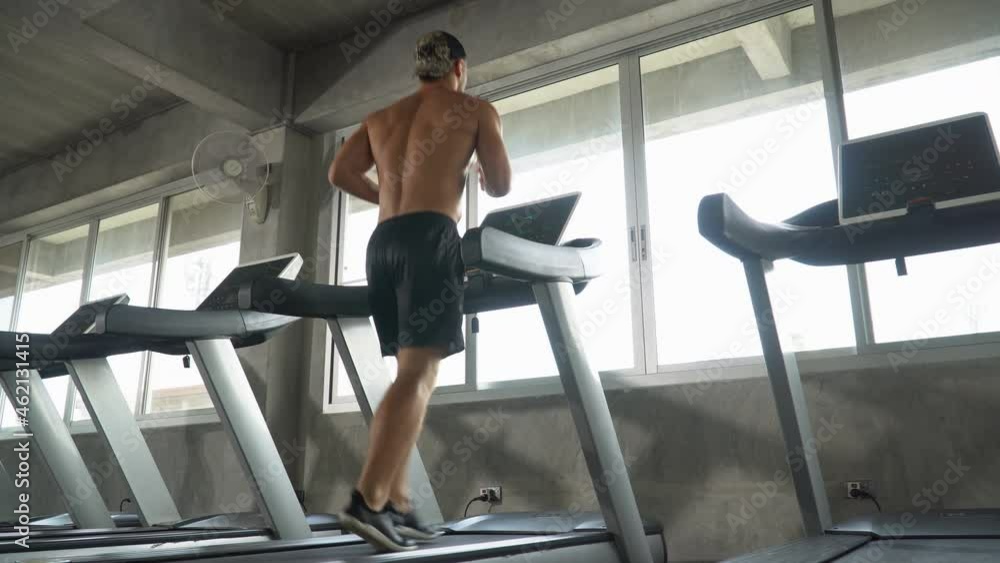 Handsome muscular man running on treadmill in fitness gym at sport club . motivation and workout . Shirtless sport guy Exercise on running Machine. bodybuilder cardio training back rear view Handsome muscular man running on treadmill in fitness gym at sport club . motivation and workout . Shirtless sport guy Exercise on running Machine. bodybuilder cardio training back rear view