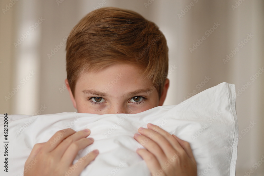 Portrait of adorable young boy hiding behind cushions. Family, vacation, childhood, care, health, stress concept Portrait of adorable young boy hiding behind cushions. Family, vacation, childhood, care, health, stress concept