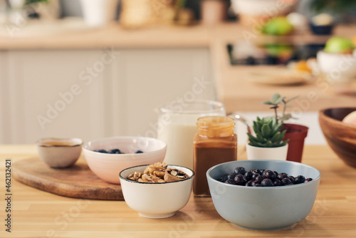 Group of bowls and jars with ingredients for smoothie on kitchen table