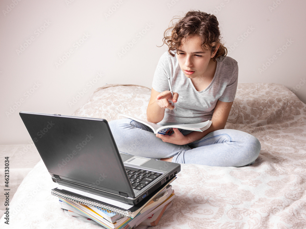 Naklejka premium Teenager girl studying online at home. School girl with lap top on the bed. Home education