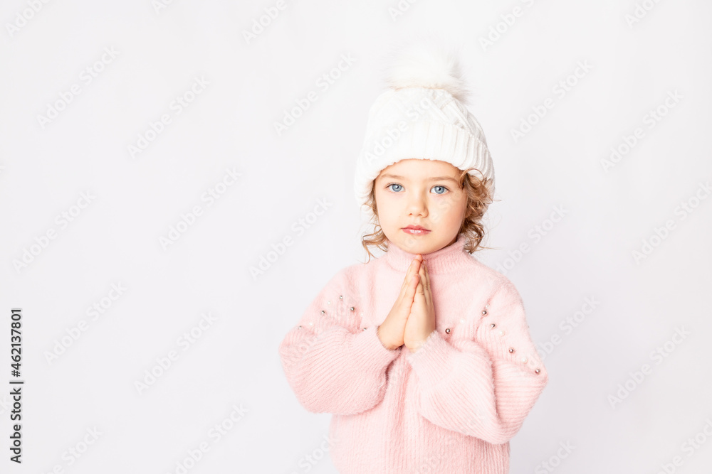beautiful child girl on a white isolated background in a pink sweater folded cute pens as if praying, space for text beautiful child girl on a white isolated background in a pink sweater folded cute pens as if praying, space for text