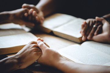 Christian worship and pray. Christian group of people holding hands praying worships together to believe and Bible on a wooden table for devotional for prayer meeting concept.