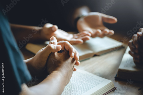 Fotografie Christian group of people holding hands praying worship to believe and Bible on a wooden table for devotional or prayer meeting concept