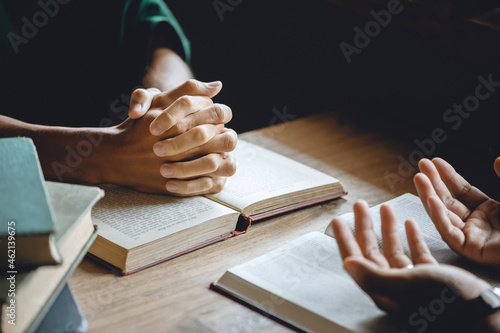 Photos Christian group of people holding hands praying worship to believe and Bible on a wooden table for devotional or prayer meeting concept