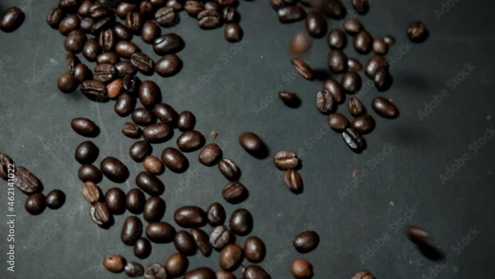 Bunch of roasted coffee beans being poured onto black surface Bunch of roasted coffee beans being poured onto black surface