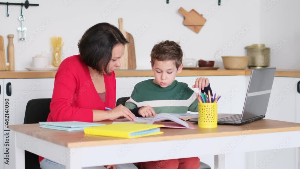 Female private tutor helping young student with homework at desk in bright child's room. mother helps son to do lessons. home schooling, home lessons. Female private tutor helping young student with homework at desk in bright child's room. mother helps son to do lessons. home schooling, home lessons.