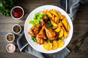 Barbecue chicken drumsticks with chips on wooden table
