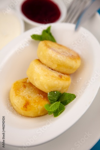 A portion of three round curd cheese pancakes on a white plate. Healthy breakfast. Food background