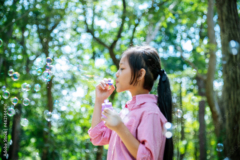 Adorable happy cute girl playful foam bubbles in green playground in summer outdoors. Funny Cheerful girl in the park with happy times. Adorable happy cute girl playful foam bubbles in green playground in summer outdoors. Funny Cheerful girl in the park with happy times.