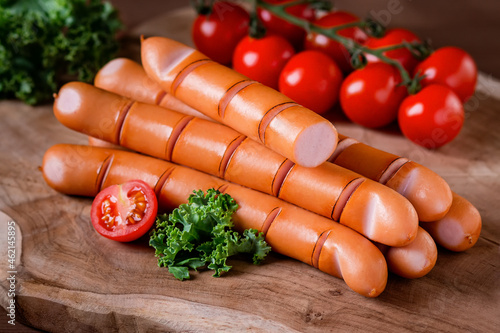 Canvas Print Styled Grilled Frankfurter sausages on wooden board with tomatoes and green herb