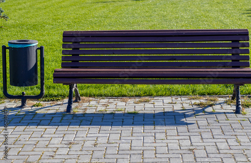 public park bench and trash bin.green grass background, walkside concept:keep clean, eco environment, relax autumn, summer.collect garbage photo