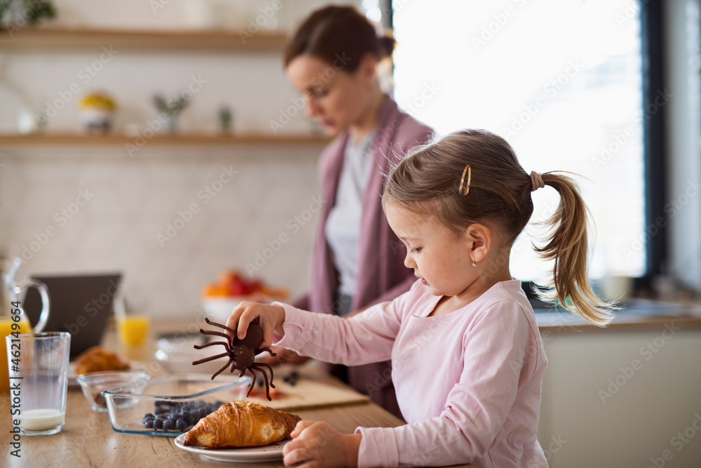 Mother with small daughter indoors in kitchen at home preparing breakfast, everyday life concept. Mother with small daughter indoors in kitchen at home preparing breakfast, everyday life concept.