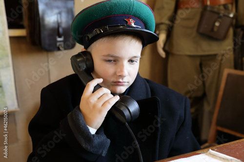 Child in uniform of border guard with telephone receiver photo