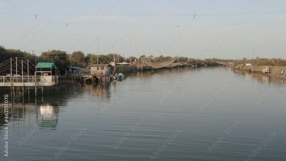 Fishermen huts with fishing nets and fishing equipment on the river at morning,Lido di Dante, Fiumi Uniti, Ravenna near Comacchio valley. Fishermen huts with fishing nets and fishing equipment on the river at morning,Lido di Dante, Fiumi Uniti, Ravenna near Comacchio valley.