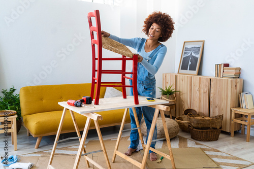 Afro woman restoring wooden chair on table at home photo