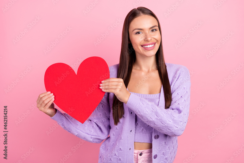 Photo of young happy positive woman hold hands heart shape red paper smile isolated on pink color background Photo of young happy positive woman hold hands heart shape red paper smile isolated on pink color background