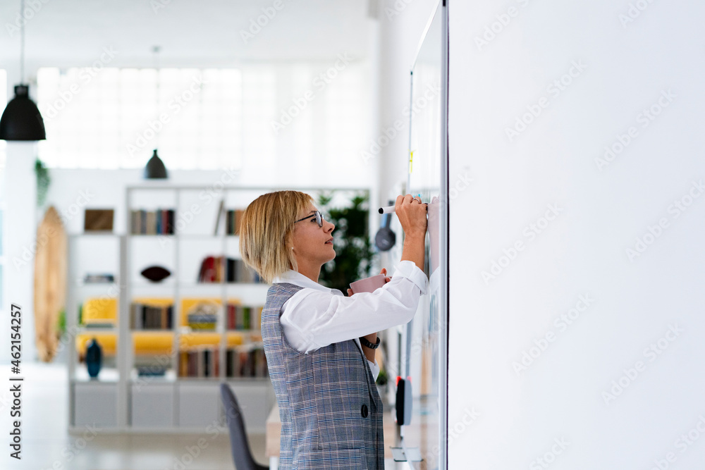 Female professional writing on whiteboard in office Female professional writing on whiteboard in office
