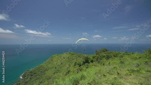 Paraglider flying over the mountain and tropical beach with blue water. Paragliding in the mountains. Active and extreme lifestyle.